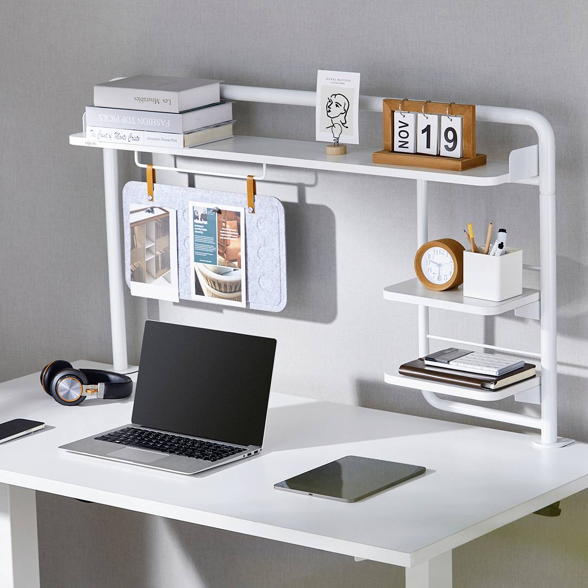 Schludnie rozłożony biurko z laptopem, notatnikiem, pojemnikiem na długopisy i datownikiem wskazującym 'Nov 19'. W tle widoczne są książki i dekoracyjna zawieszka.