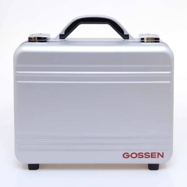 Srebrna walizka z czarną rączką i czerwonym logo 'Gossen' w prawym dolnym rogu.