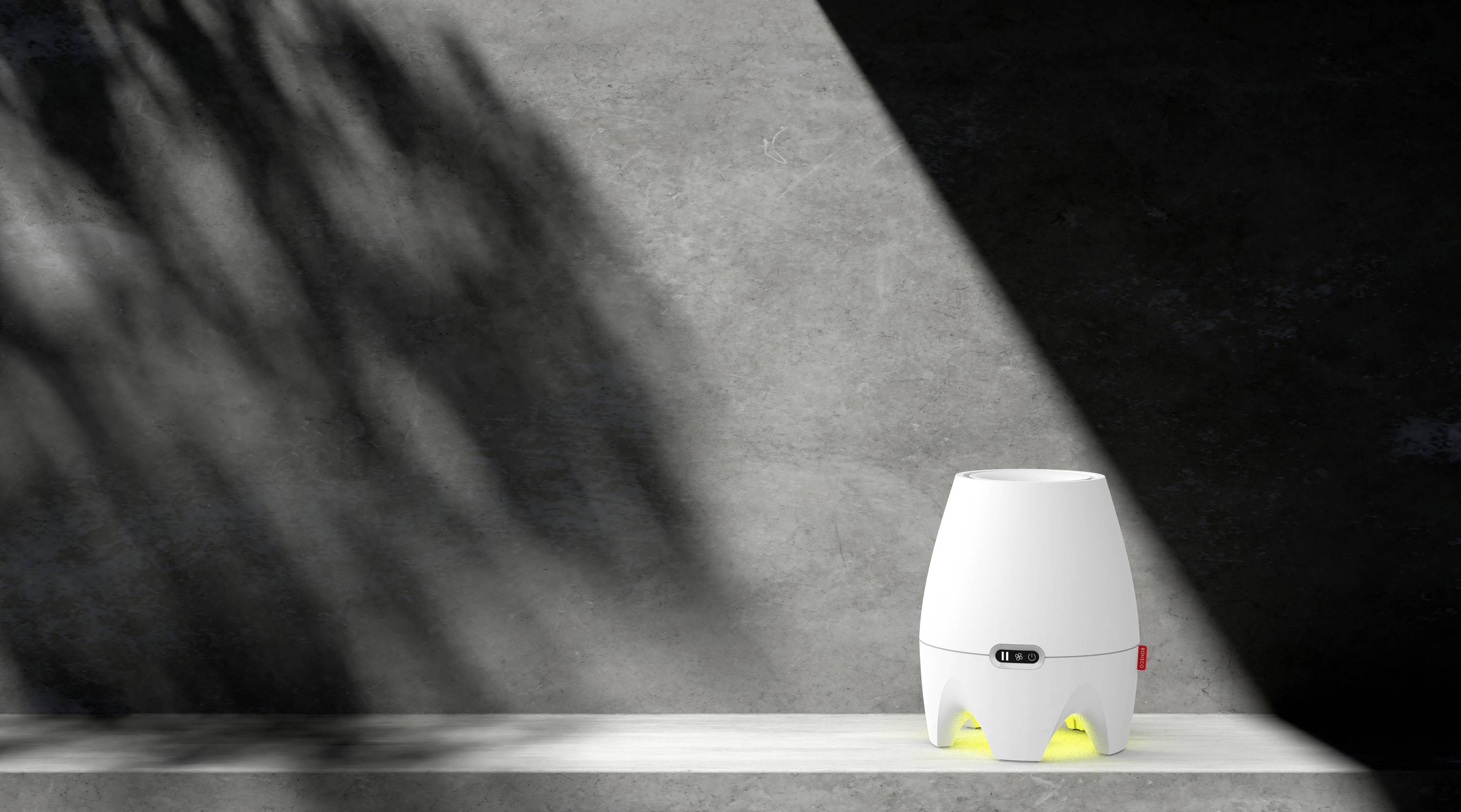 Biała, jajowata lampa stojąca na stole; rzuca ciepłe, żółte światło. W tle cienie roślin na szarej ścianie.