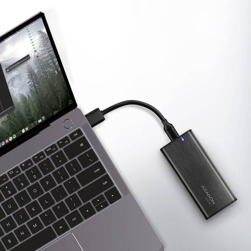 Laptop jest podłączony do przenośnego dysku twardego za pomocą kabla USB. Na ekranie widoczne są otwarte okna.