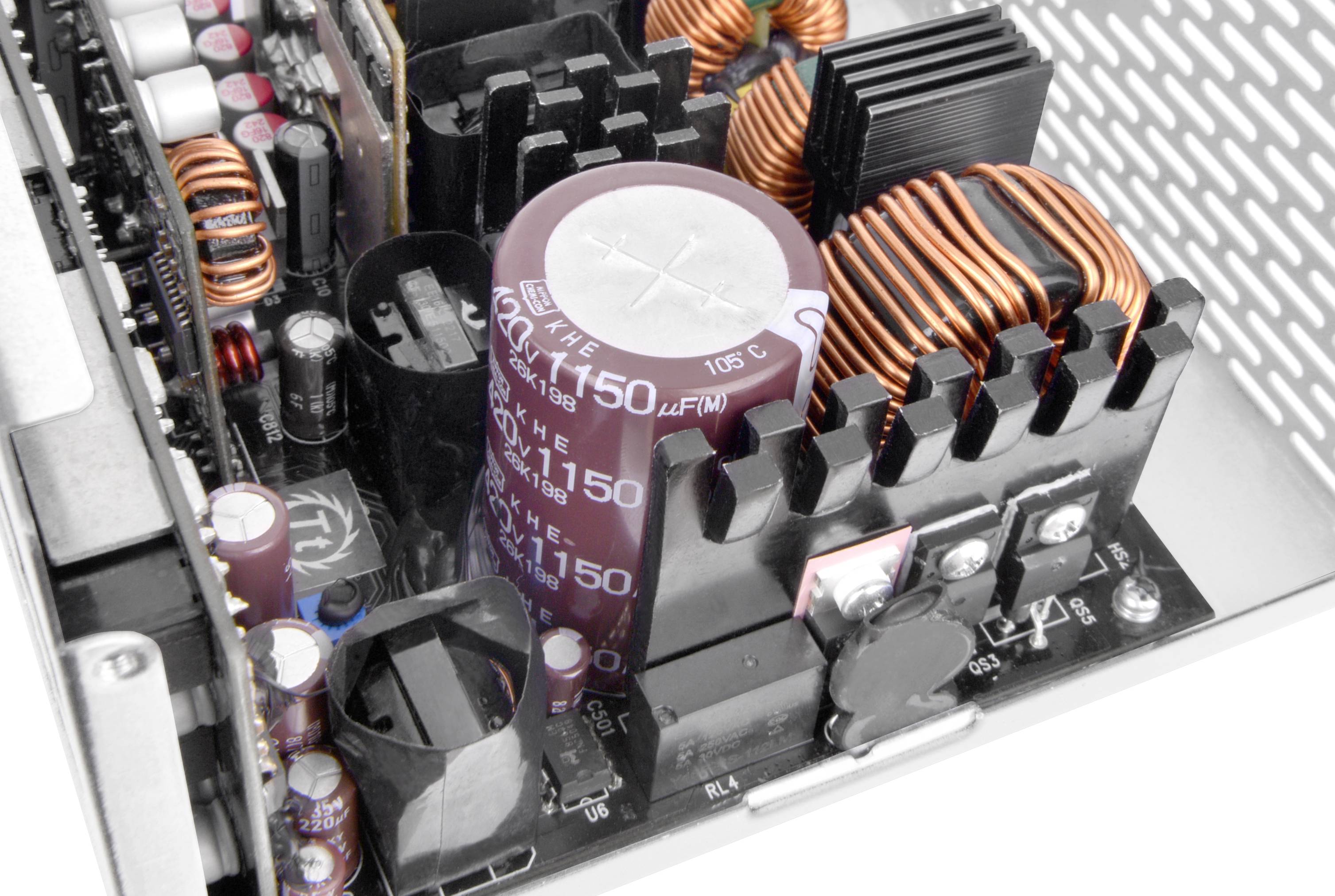 Elektroniczne komponenty zasilacza komputerowego, w tym duże kondensatory i cewki miedziane, które są kluczowe dla zasilania.