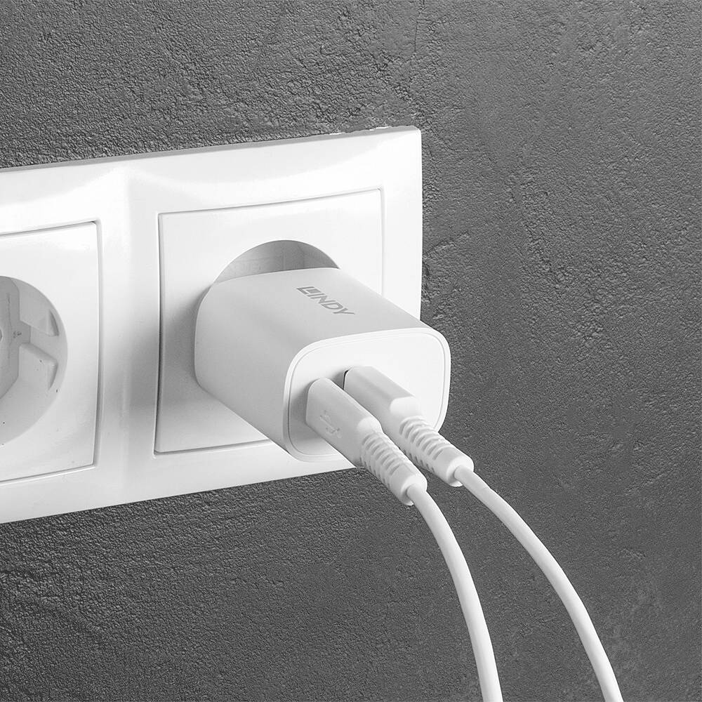 Ładowarka jest podłączona do gniazdka ściennego z dwoma przewodami wprowadzonymi z lewej strony do ładowarki.