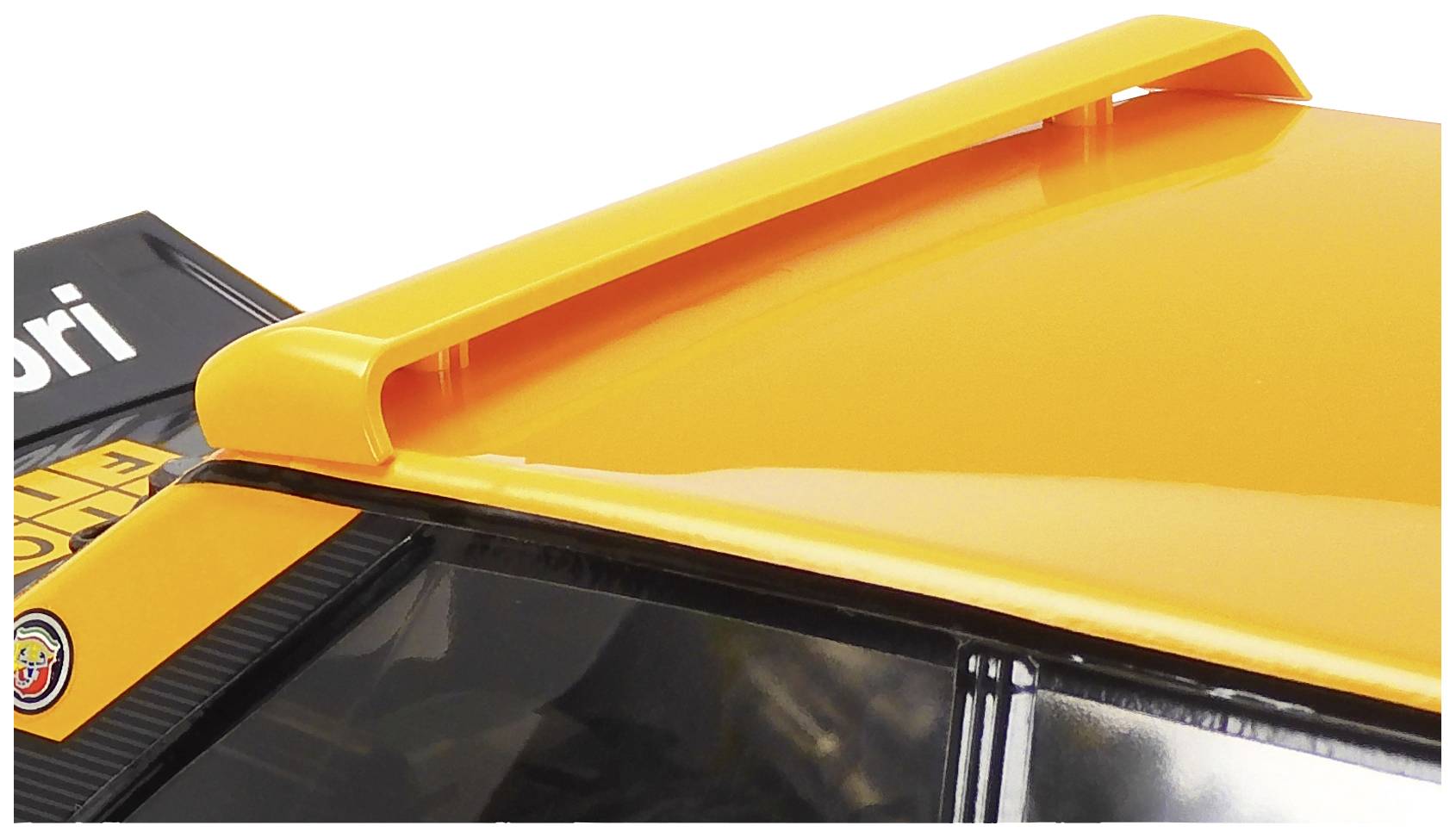 Pomarańczowy spoiler na dachu pojazdu, obok częściowo widocznego logo.