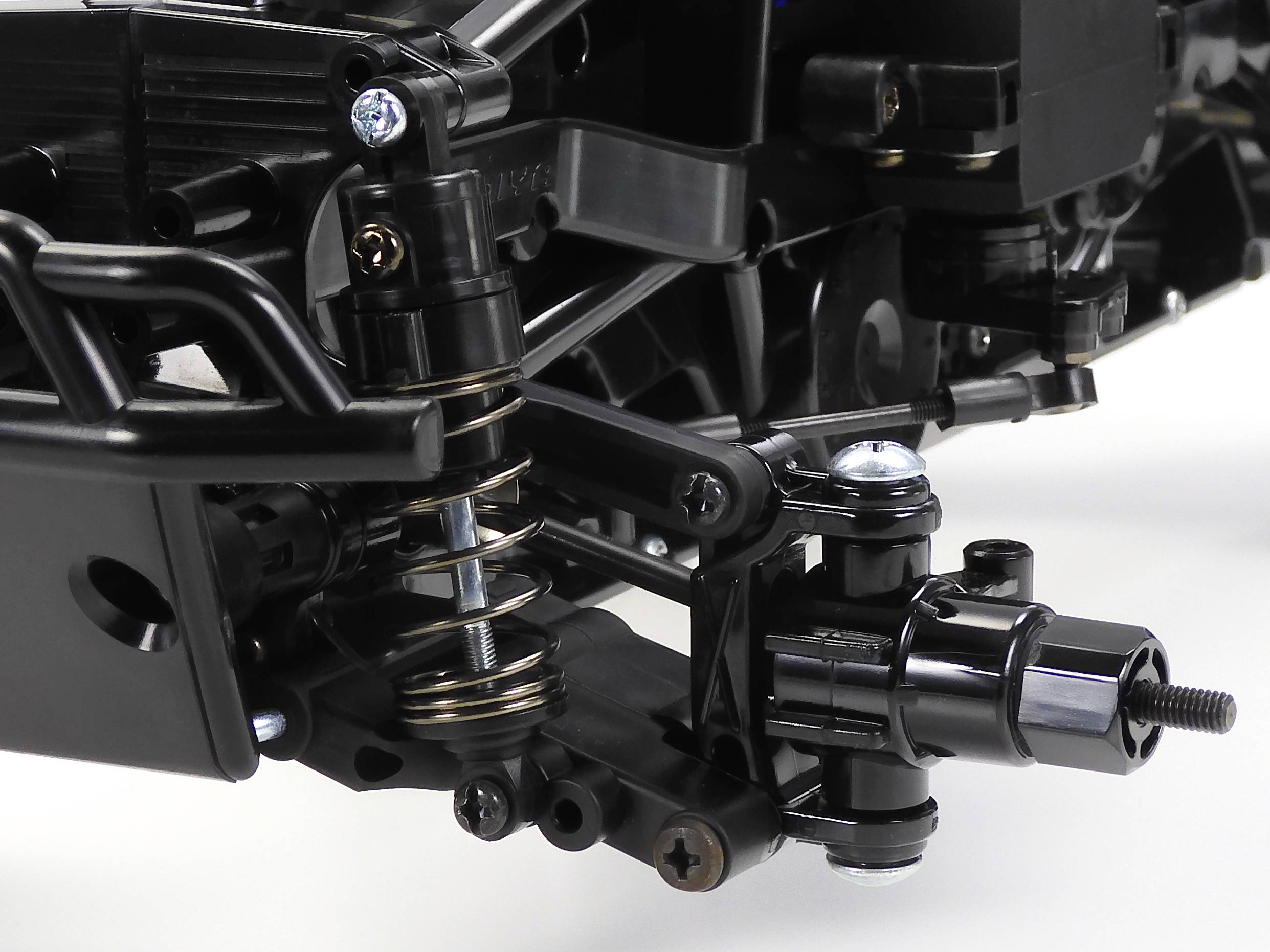 Zbliżenie mechanizmu zawieszenia z amortyzatorem na podwoziu pojazdu. Wyraźnie widoczne są sprężyny i mocowania.