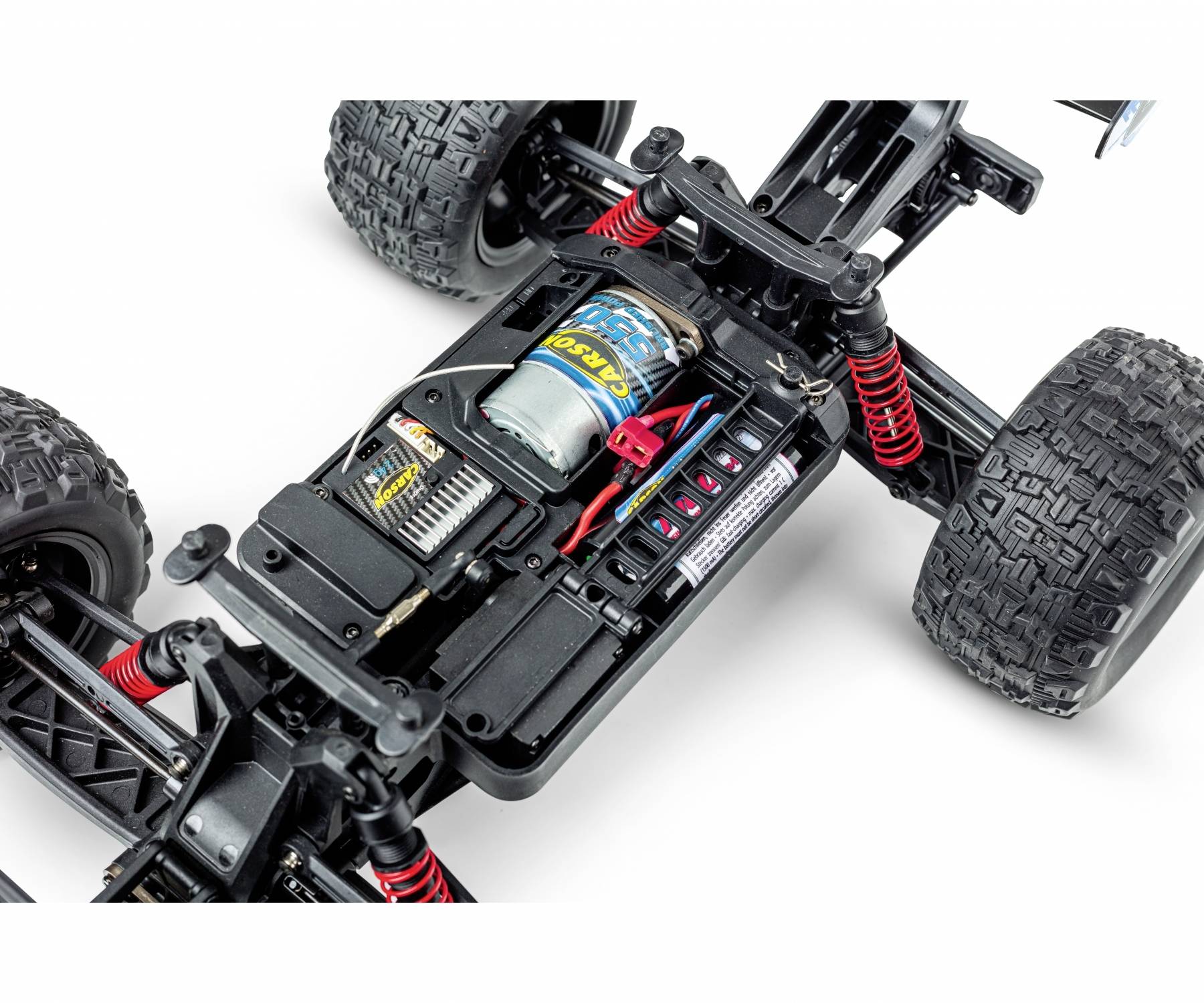 Zbliżenie zdalnie sterowanego samochodu bez nadwozia, ukazujące silnik, zawieszenie i komorę akumulatora. Wyraźny widok szczegółów technicznych.