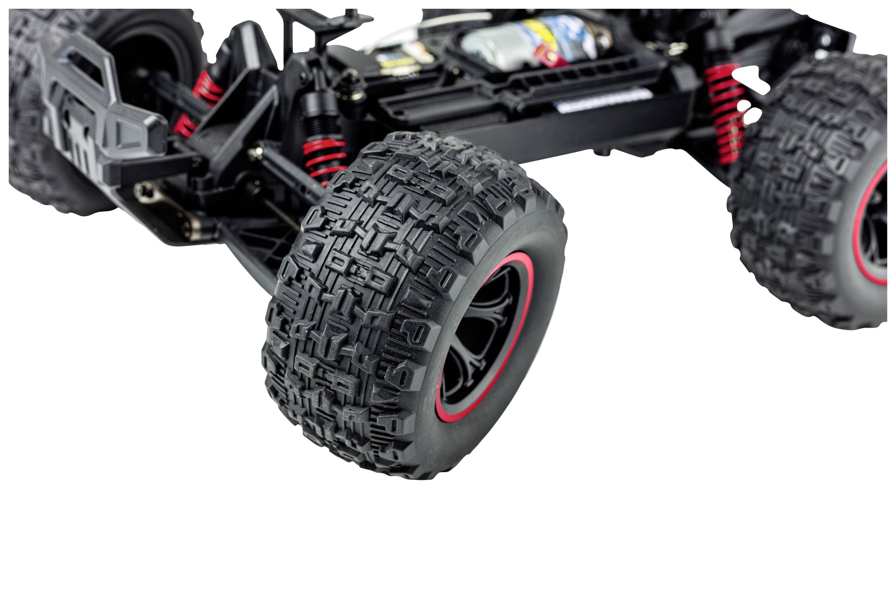Zbliżenie zdalnie sterowanego samochodu; fokus na wytrzymałych, czarno-czerwonych oponach terenowych i zawieszeniu.