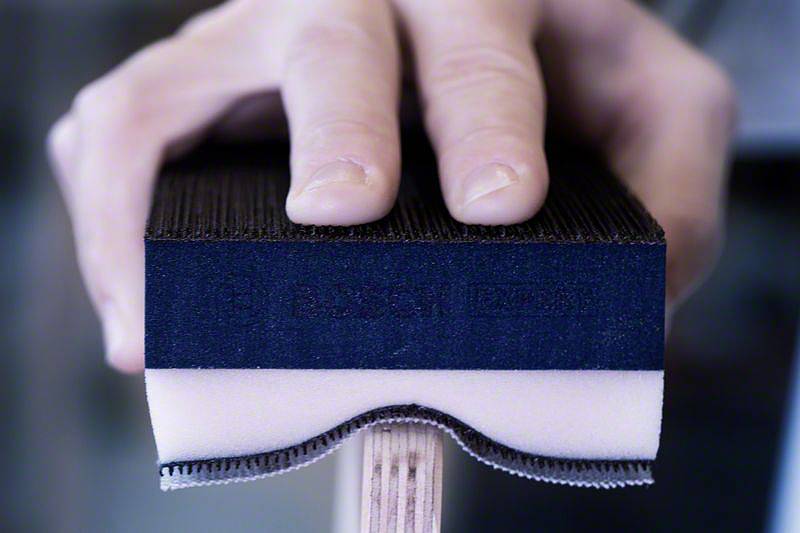 Zbliżenie dłoni trzymającej rakietę do ping-ponga. Ostrość skierowana jest na powierzchnię rakiety i czubki palców.