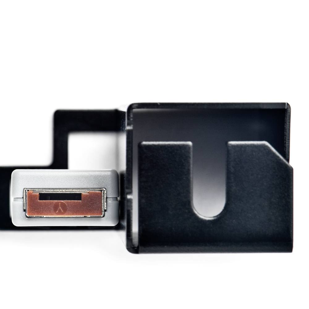 Klucz tkwi w czarnym uchwycie zamocowanym na ścianie. Uchwyt ma zakrzywiony kształt i jest przymocowany do gładkiej powierzchni.