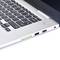 Srebrny laptop z czarną klawiaturą w zbliżeniu, z wyróżniającym się zielonym modułem karty pamięci, częściowo włożonym.