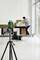 Mężczyzna nakłada czarne i białe płytki na ścianę. Zielony laser poziomujący na statywie rzuca linie wyrównawcze.
