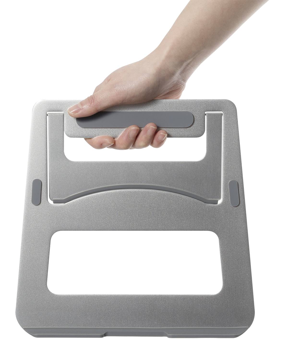 Dłoń trzyma kwadratowy, szary uchwyt transportowy wykonany z metalu o zaokrąglonych krawędziach i prostokątnym wycięciu pośrodku.