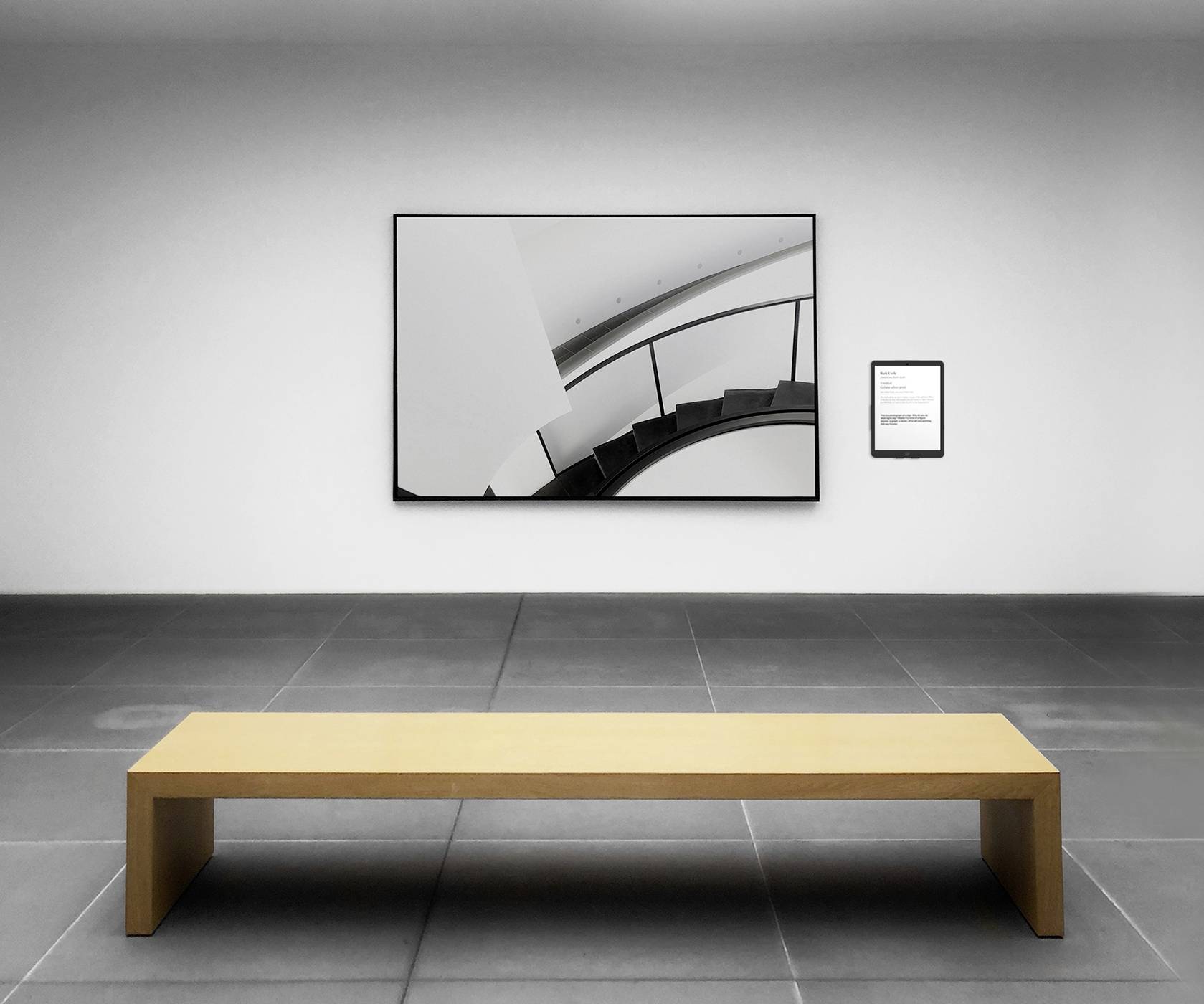 Minimalistyczne wnętrze z drewnianą ławką pośrodku, przed nowoczesnym, abstrakcyjnym dziełem sztuki wiszącym na ścianie.