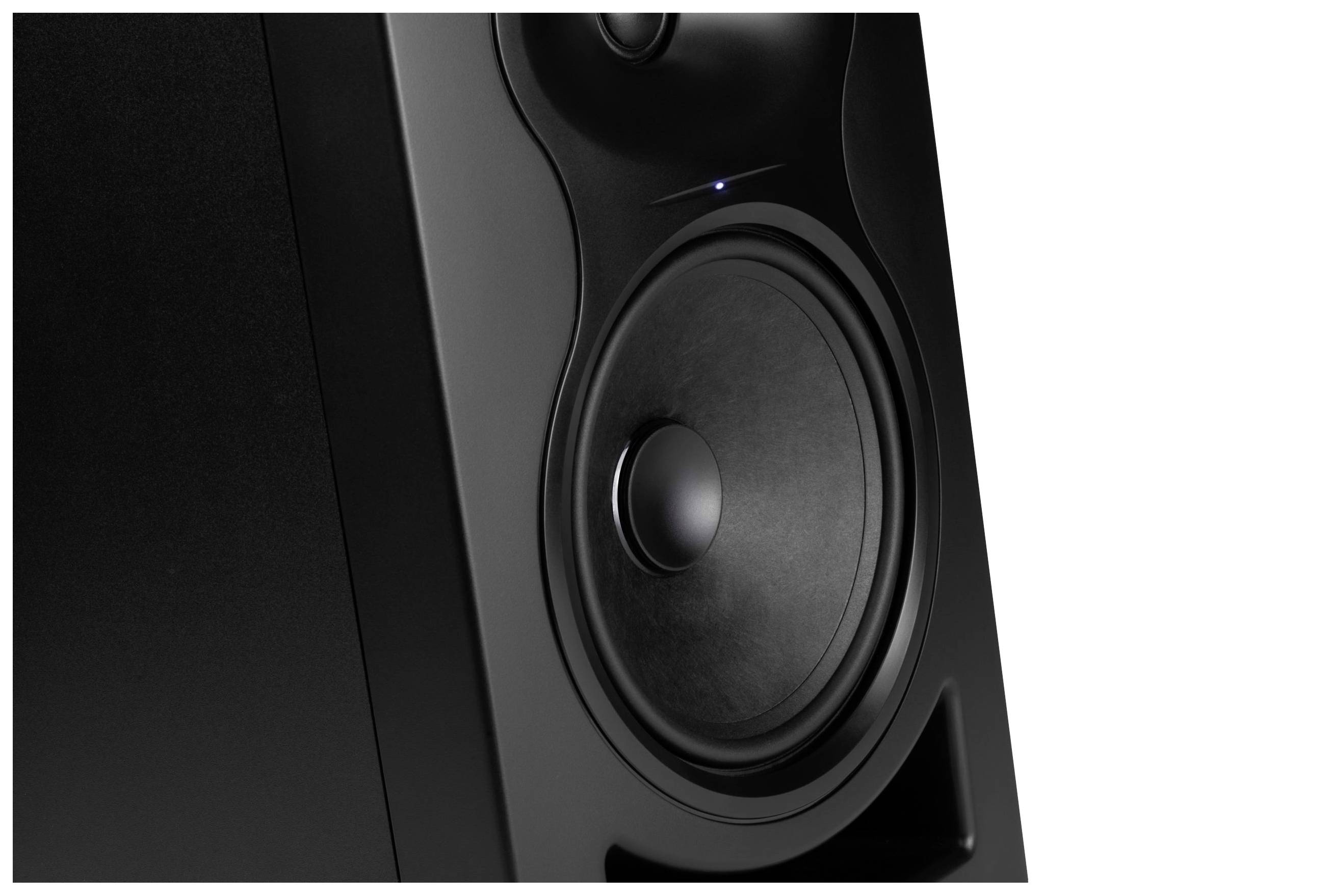 Czarny głośnik w zbliżeniu, z widocznym dużym głośnikiem niskotonowym i małą diodą LED powyżej, stanowiący element systemu audio.