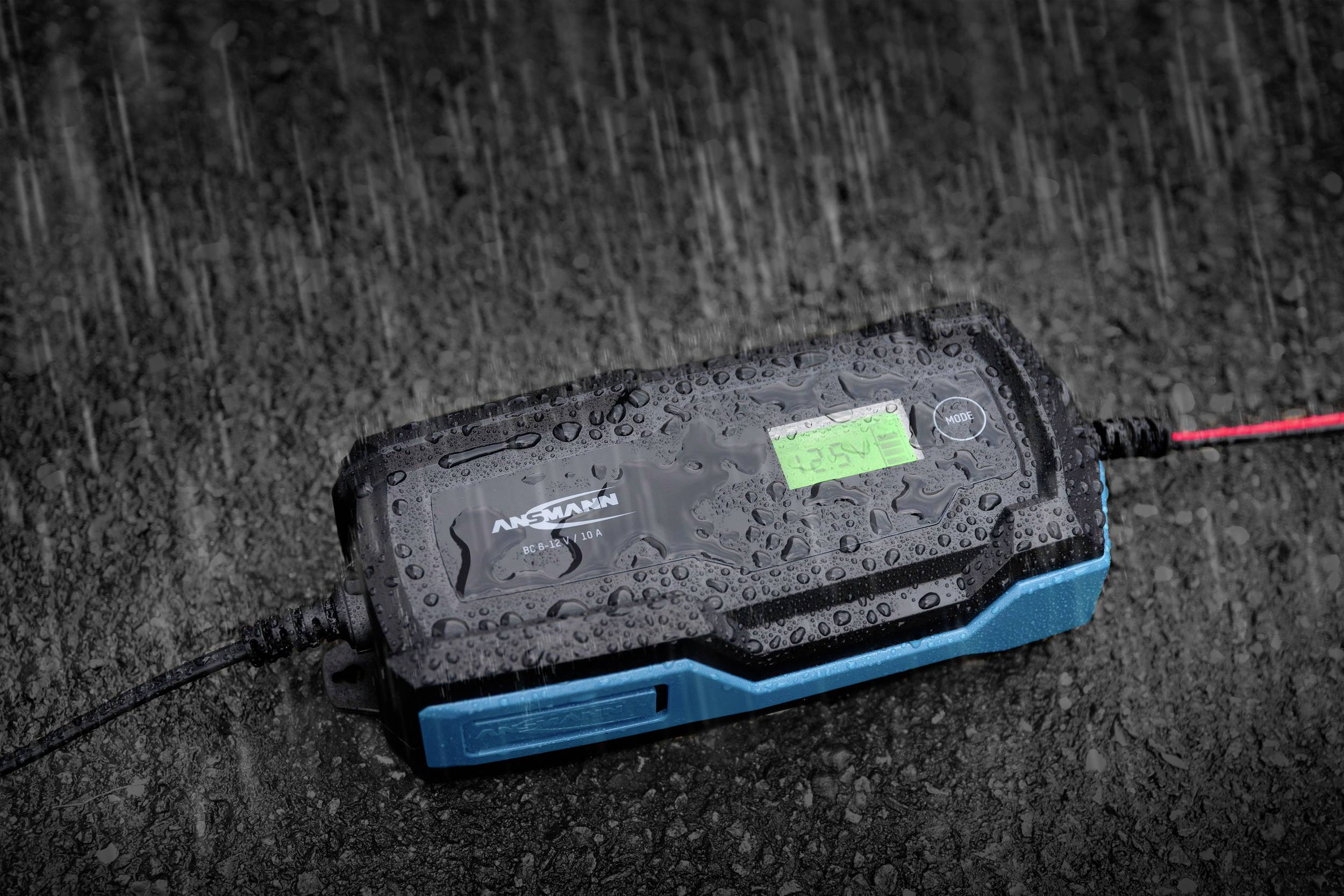 Ładowarka zasilana baterią leży na mokrym asfalcie podczas silnego deszczu.