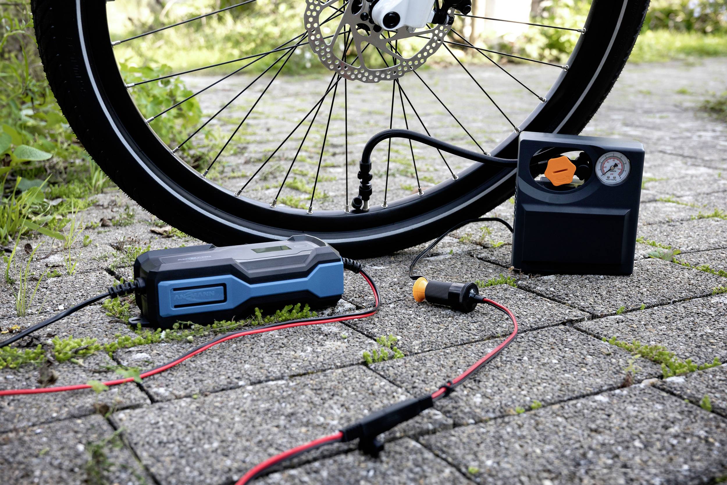 Opona rowerowa jest pompowana przenośną pompką rowerową na brukowanej drodze.