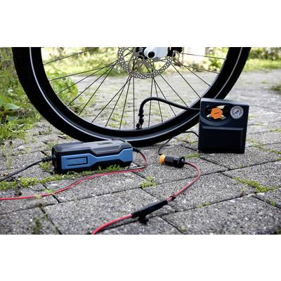 Opona rowerowa jest pompowana przenośną pompką rowerową na brukowanej drodze.