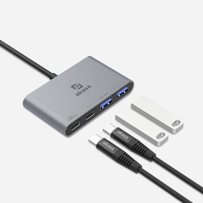 Koncentrator USB z dwoma portami USB-C i dwoma portami USB-A, zasilaczem, kablem USB-C oraz kablem USB-A, wszystkie w kolorze szarym.
