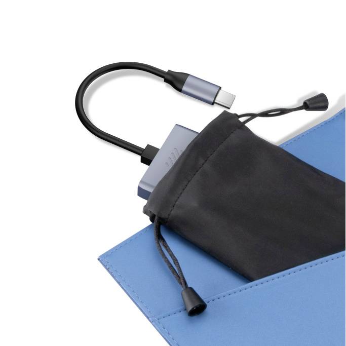 Adapter USB-C leży częściowo wysunięty z czarnej torby materiałowej na niebieskim podłożu.