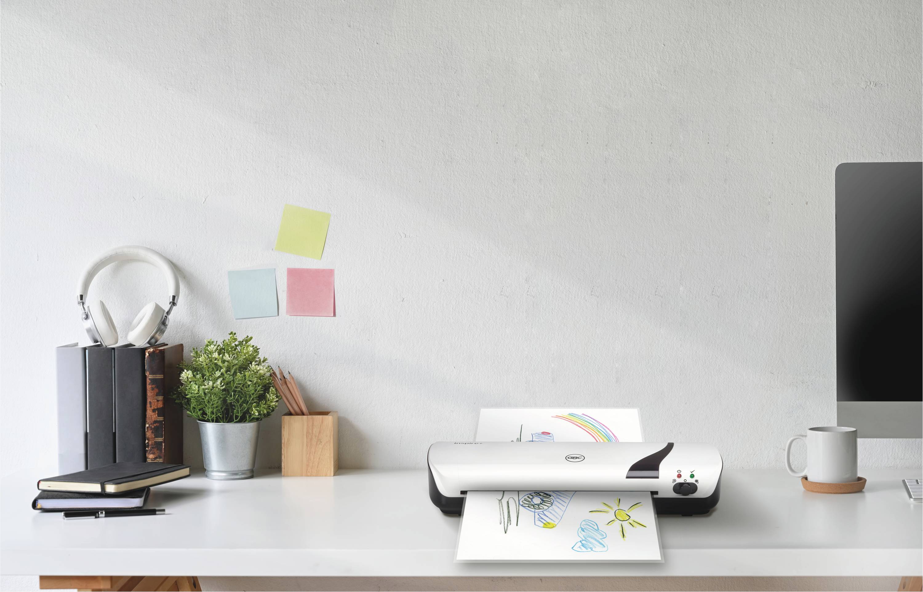 Biurko z skanerem, który skanuje rysunek słońca i chmur. Obok ustawione są rośliny, książki i słuchawki.