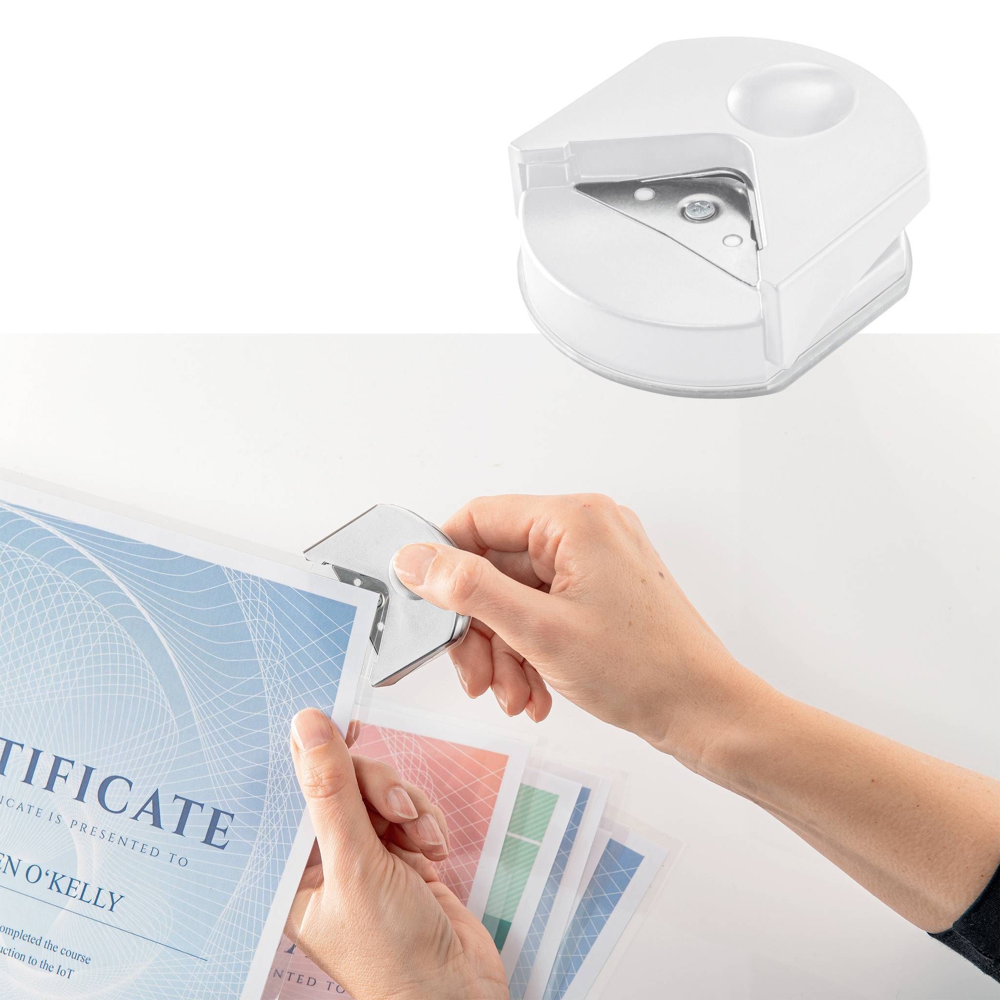 Osoba używa okrągłego urządzenia do dziurkowania w celu zaokrąglenia rogów certyfikatów.