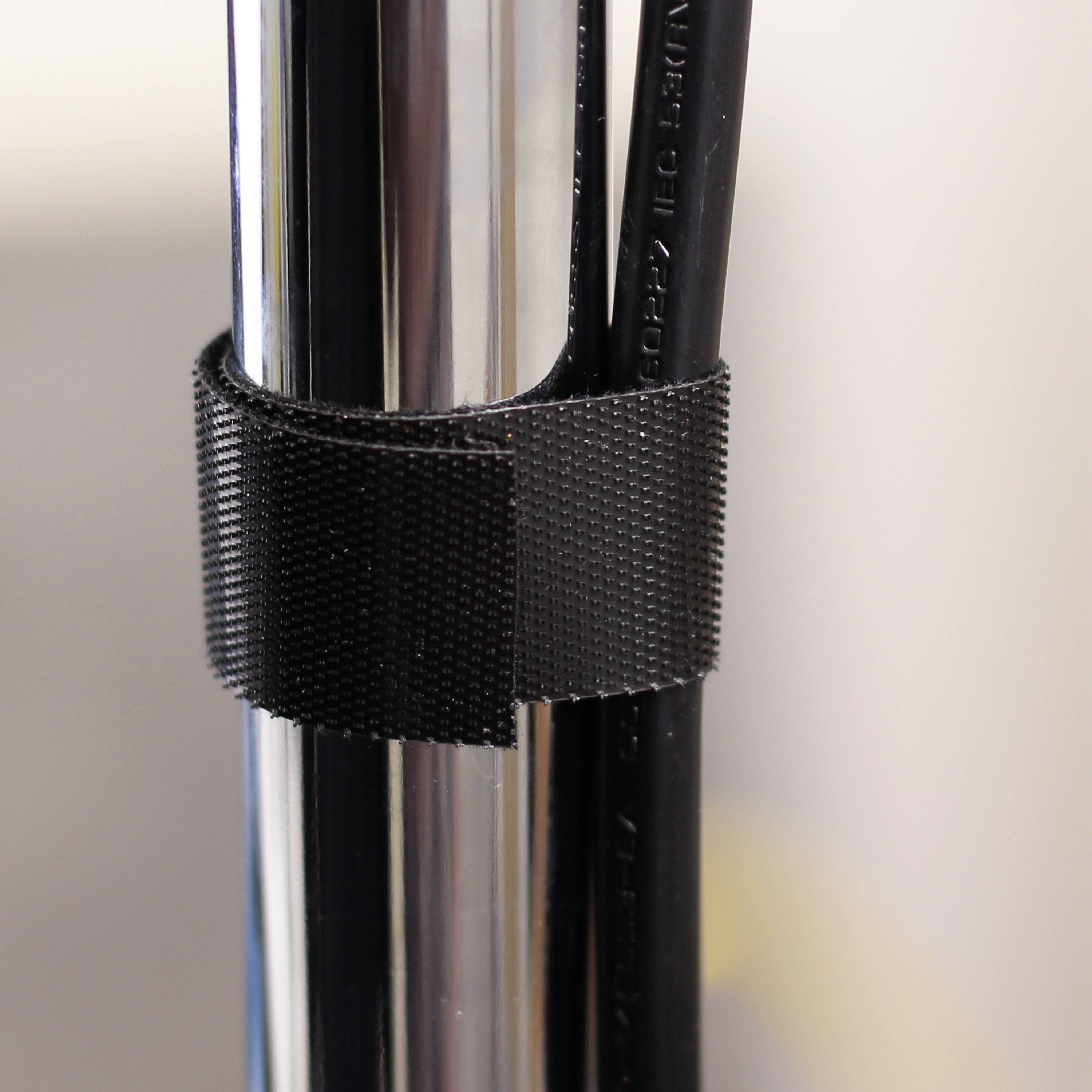 Zbliżenie czarnej opaski zaciskowej łączącej razem kilka przewodów i metalowych prętów.