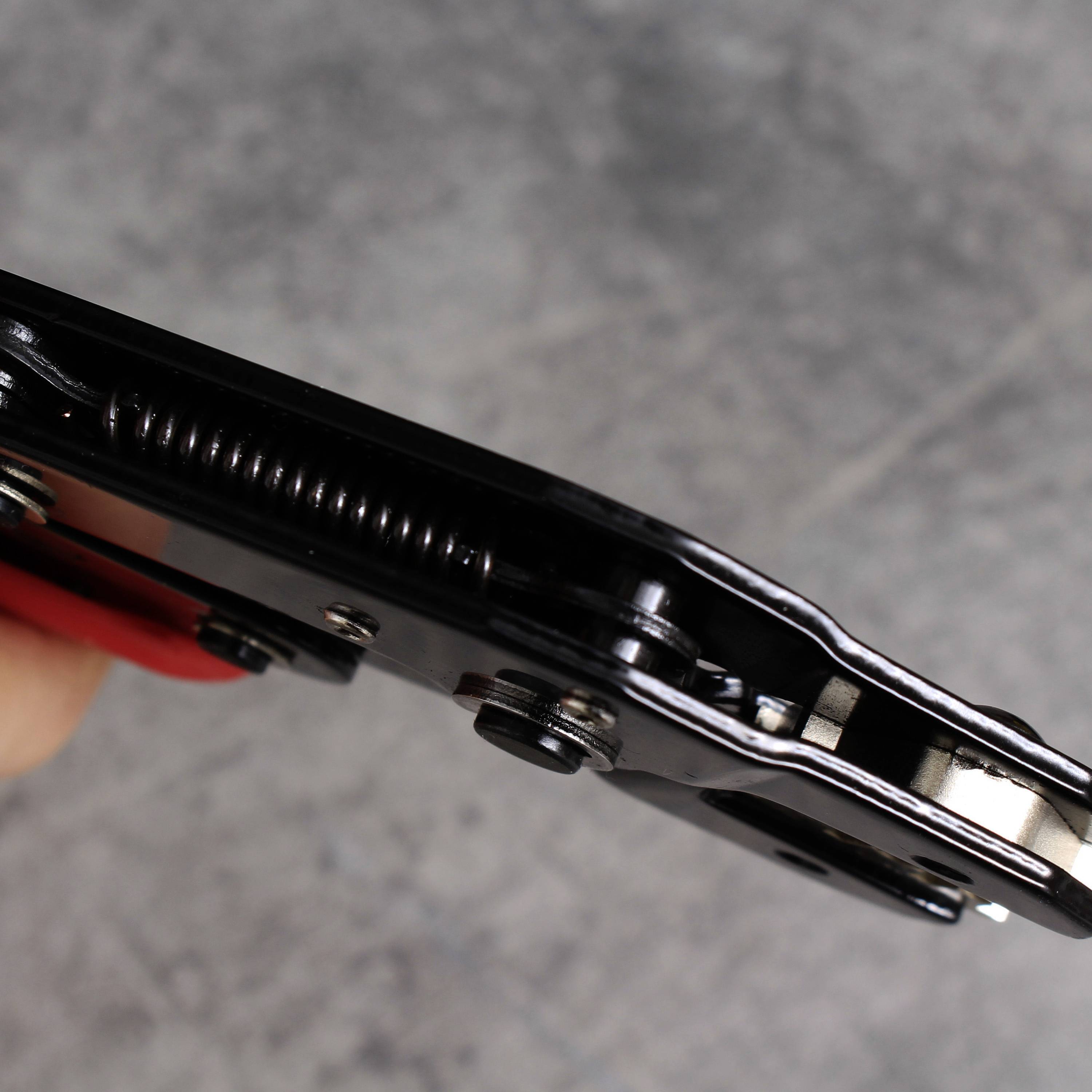 Zbliżenie czarnego zawiasu z widocznymi piórami i śrubami na szarym tle.