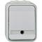 Prostokątny, biały włącznik światła z osłoną, przeznaczony do pomieszczeń wilgotnych. Bez widocznych oznaczeń lub przycisków.
