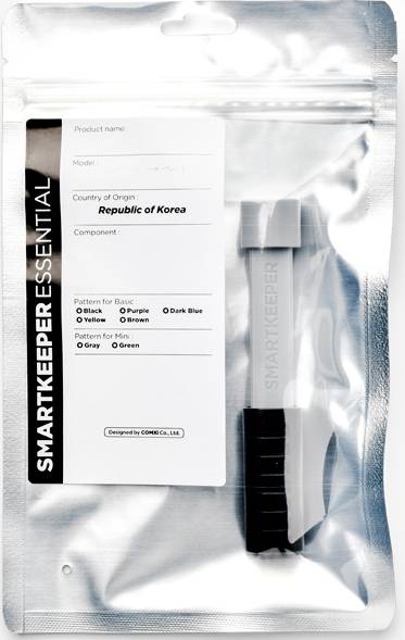 Przezroczyste opakowanie z akcesoriami, oznaczone napisem 'Smart Keeper Essential, Republika Korei'. Zawiera szare urządzenie zabezpieczające.