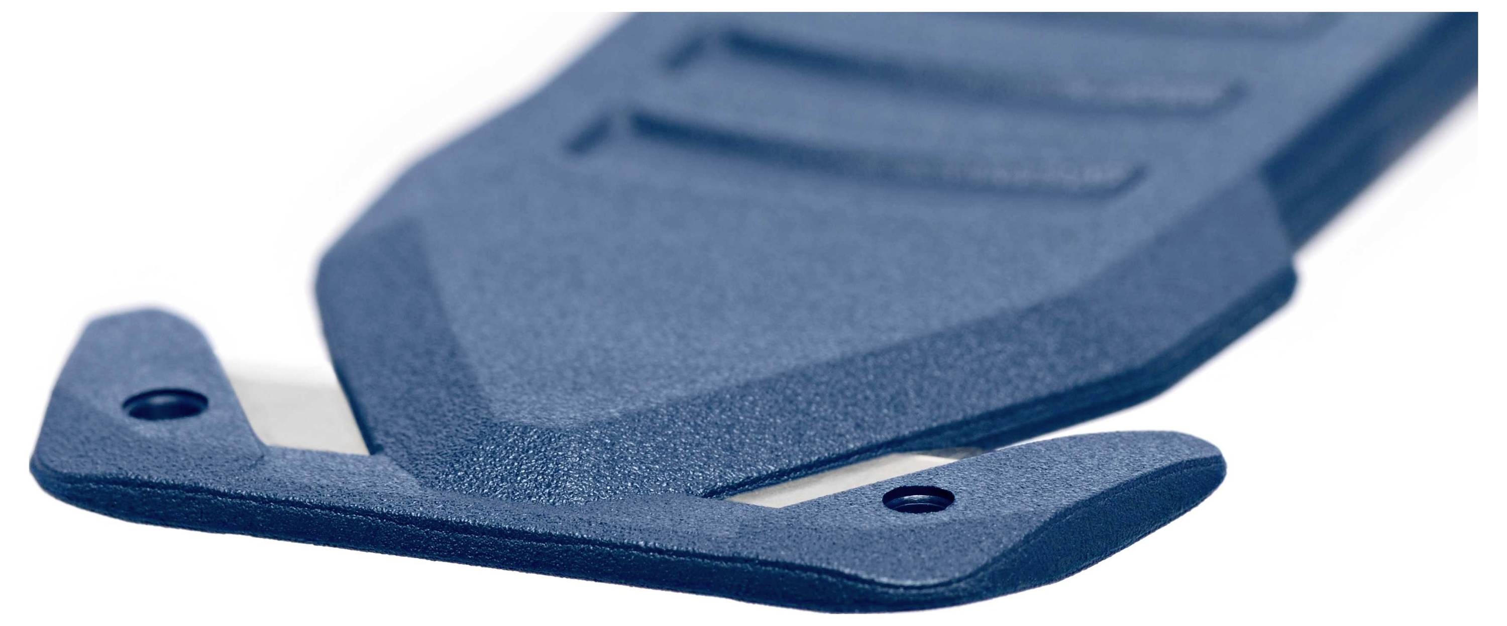 Zbliżenie niebieskiej, ergonomicznie ukształtowanej ostrej krawędzi noża z osłoną ochronną.