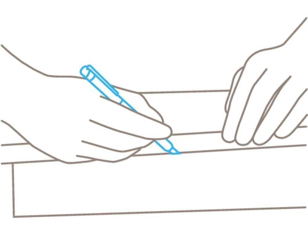 Jedna ręka trzyma długopis i rysuje linię na powierzchni, podczas gdy druga ręka przytrzymuje materiał.