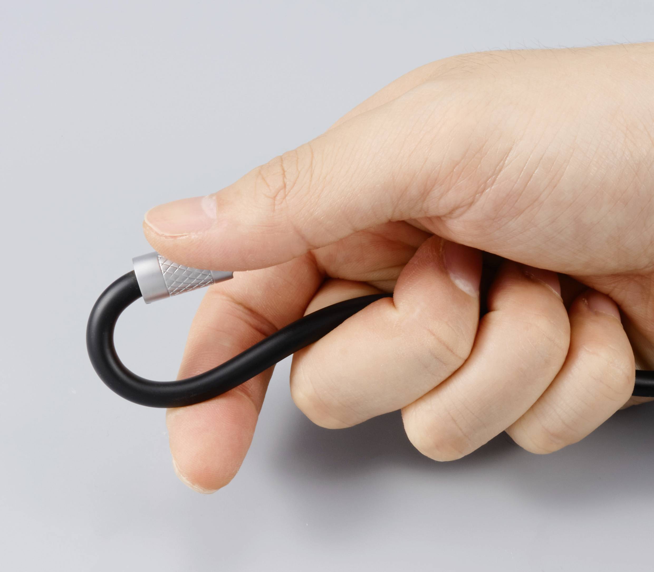 Jedna ręka trzyma czarny kabel zagięty w pętlę.