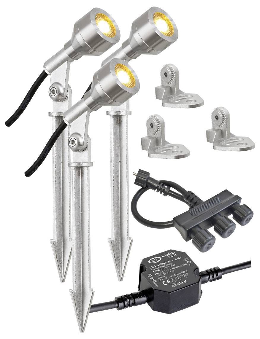 Trzy metalowe reflektory naziemne ze stakami, uchwytami montażowymi, złączem zasilającym i transformatorem pokazane na białym tle.