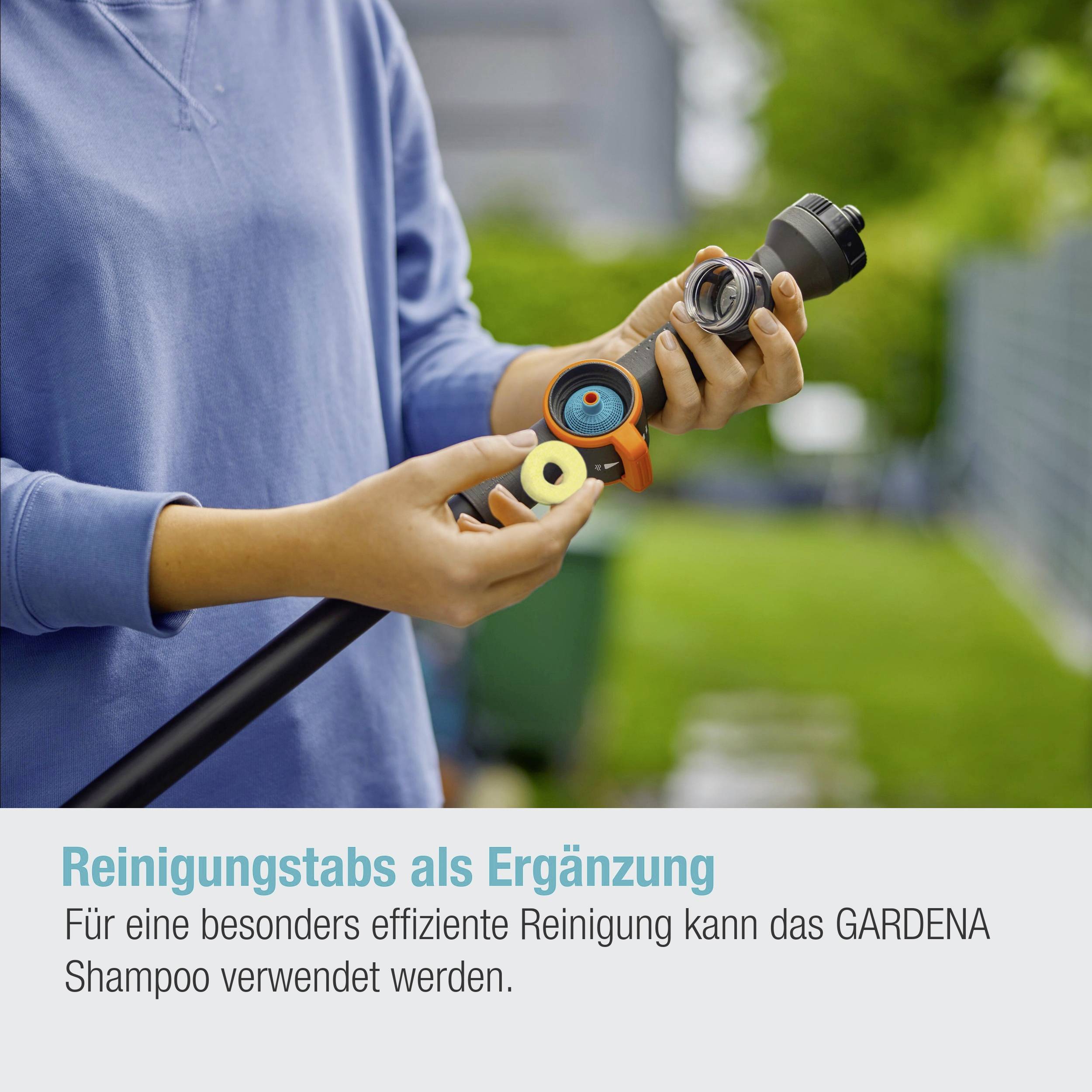 Osoba trzyma złączkę wężową z nasadką czyszczącą. Tekst poniżej: 'Jako uzupełnienie można użyć środka czyszczącego GARDENA Shampoo.'