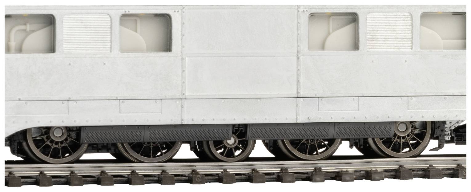 Widok z boku modelu wagonu kolejowego w kolorze szaro-białym z widocznymi kołami na torach.