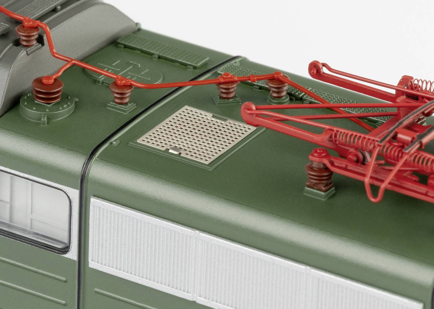 Widok z góry zielonej lokomotywy modelowej z widocznymi czerwonymi pantografami i szczegółami struktury dachu.