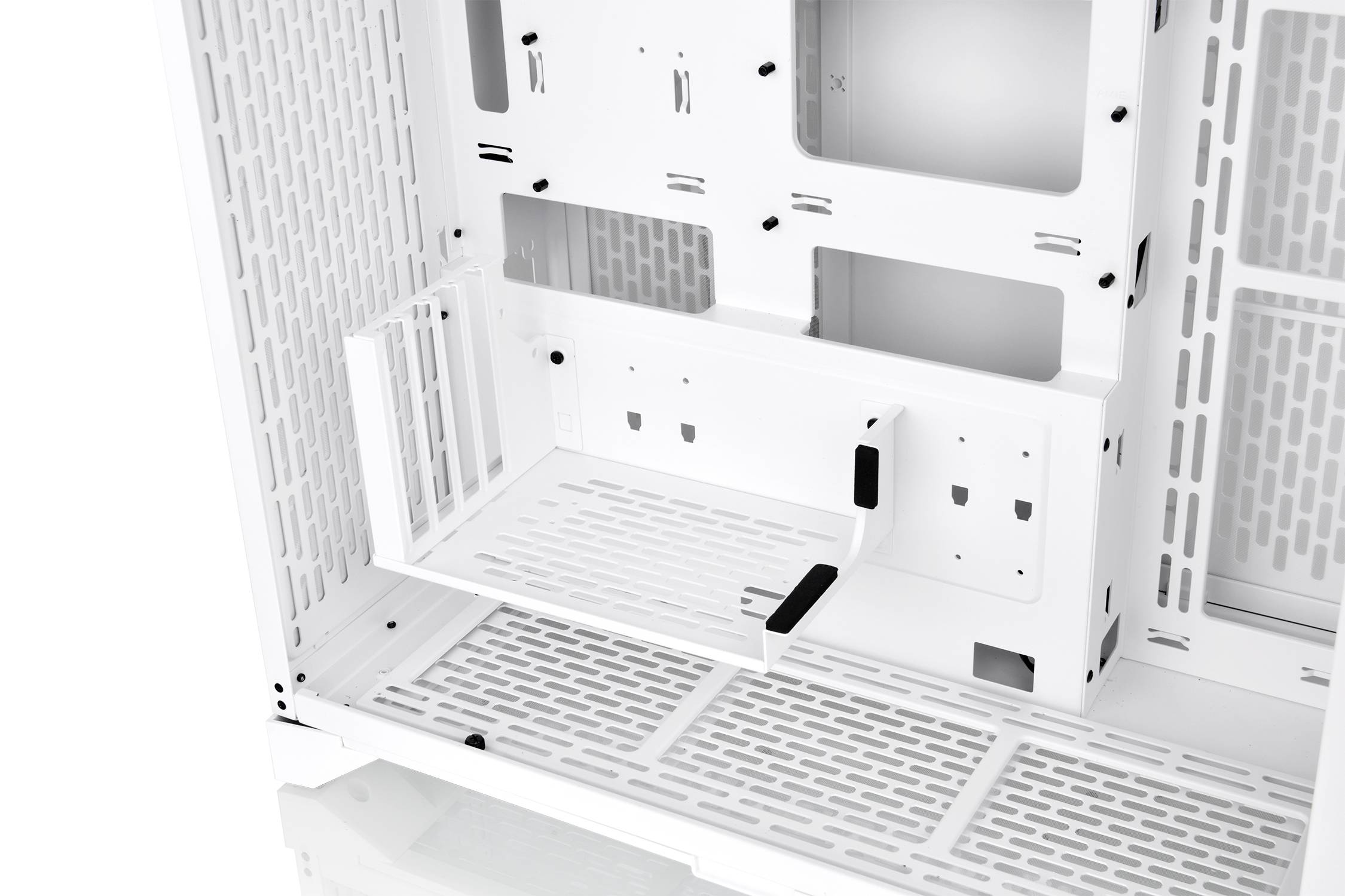 Widok wewnętrzny białej obudowy komputera z wentylowanym spodem i miejscem na montaż podzespołów. Po lewej stronie koszyk na napędy.