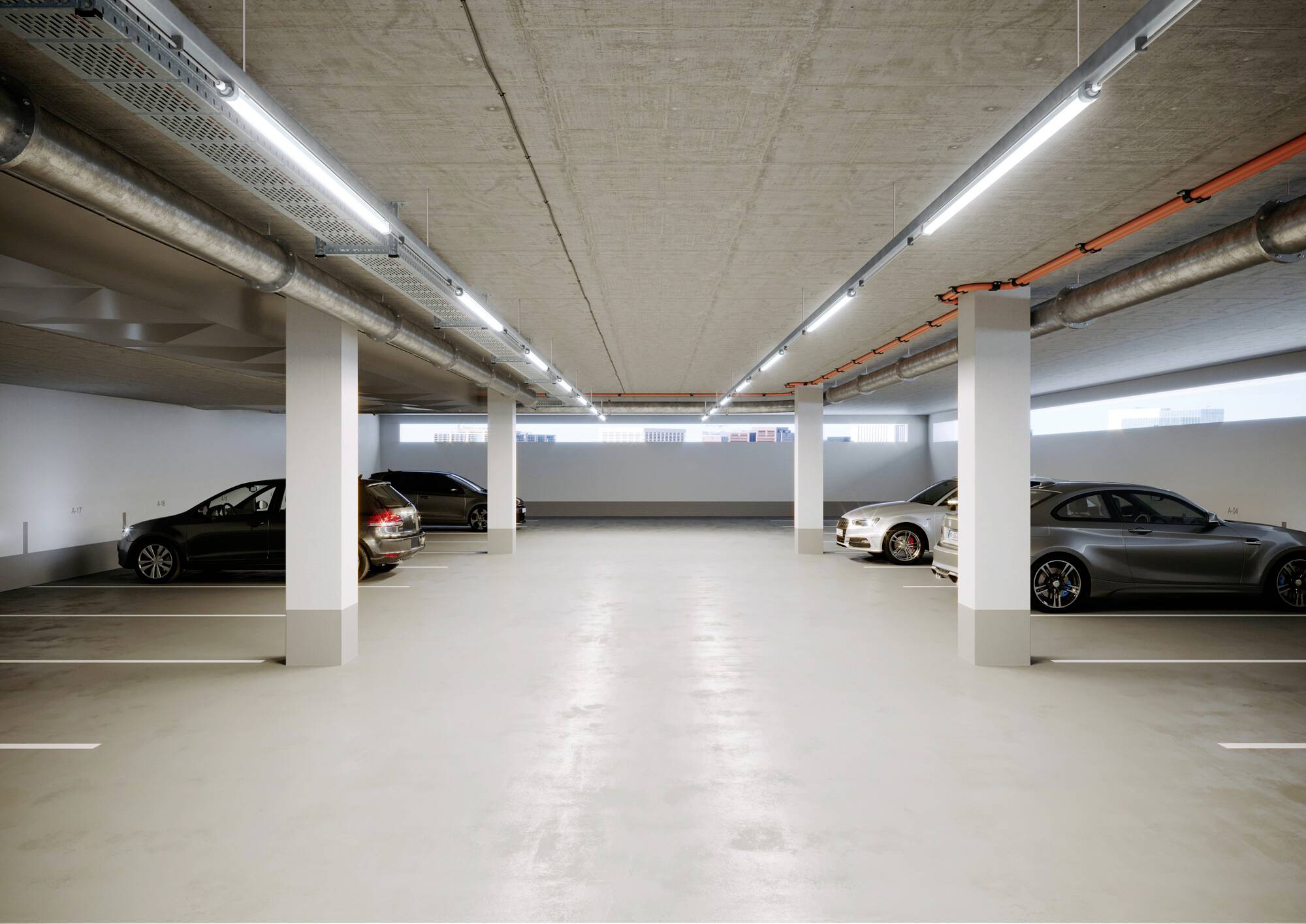 Nowoczesna, dobrze oświetlona przestrzeń parkingu podziemnego z czterema zaparkowanymi samochodami. Widoczne są rury wentylacyjne i betonowe ściany.