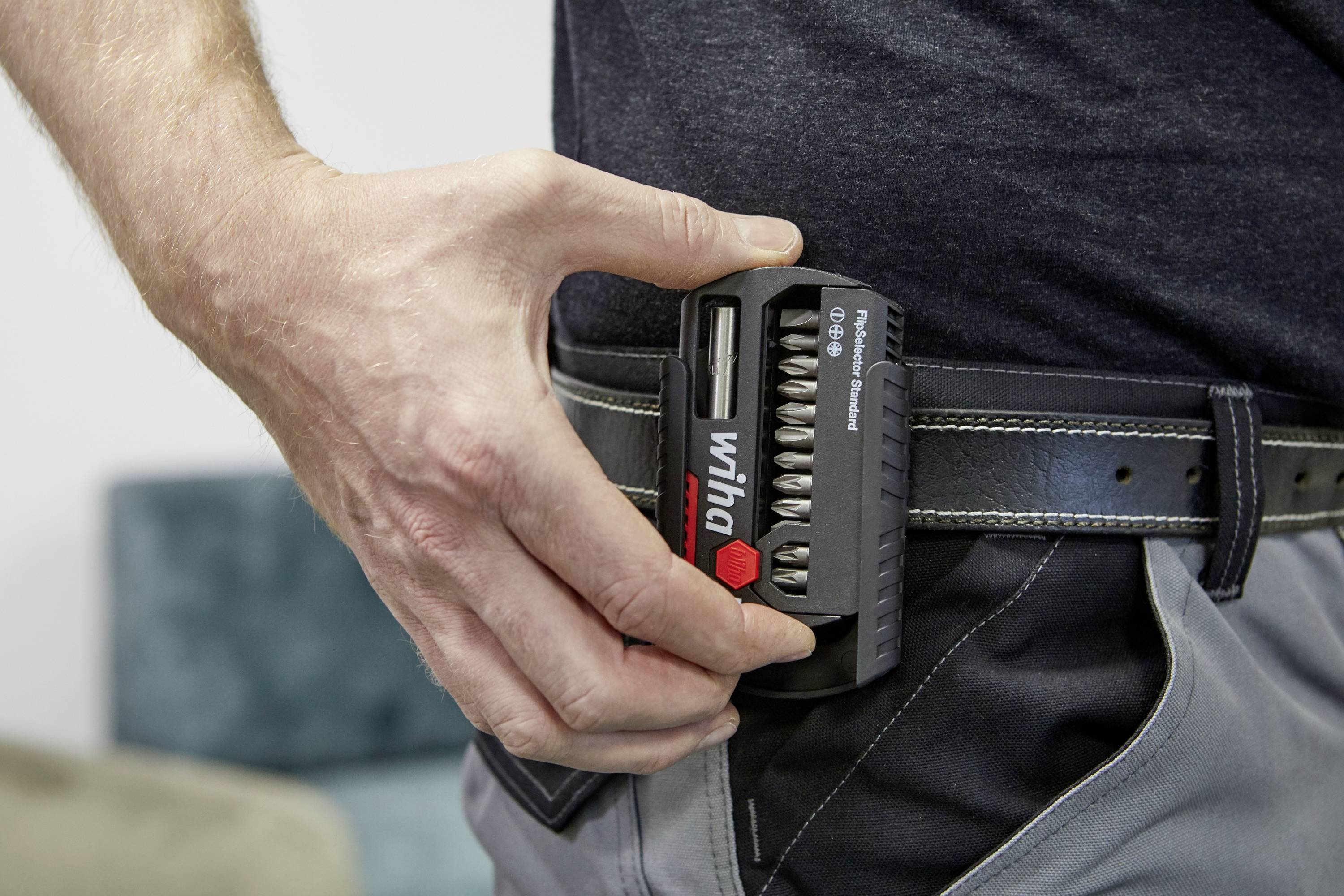 Osoba wkłada zestaw bitów Wiha do etui na pas. Zestaw zawiera różne bity i jest umieszczony w czarnym uchwycie.