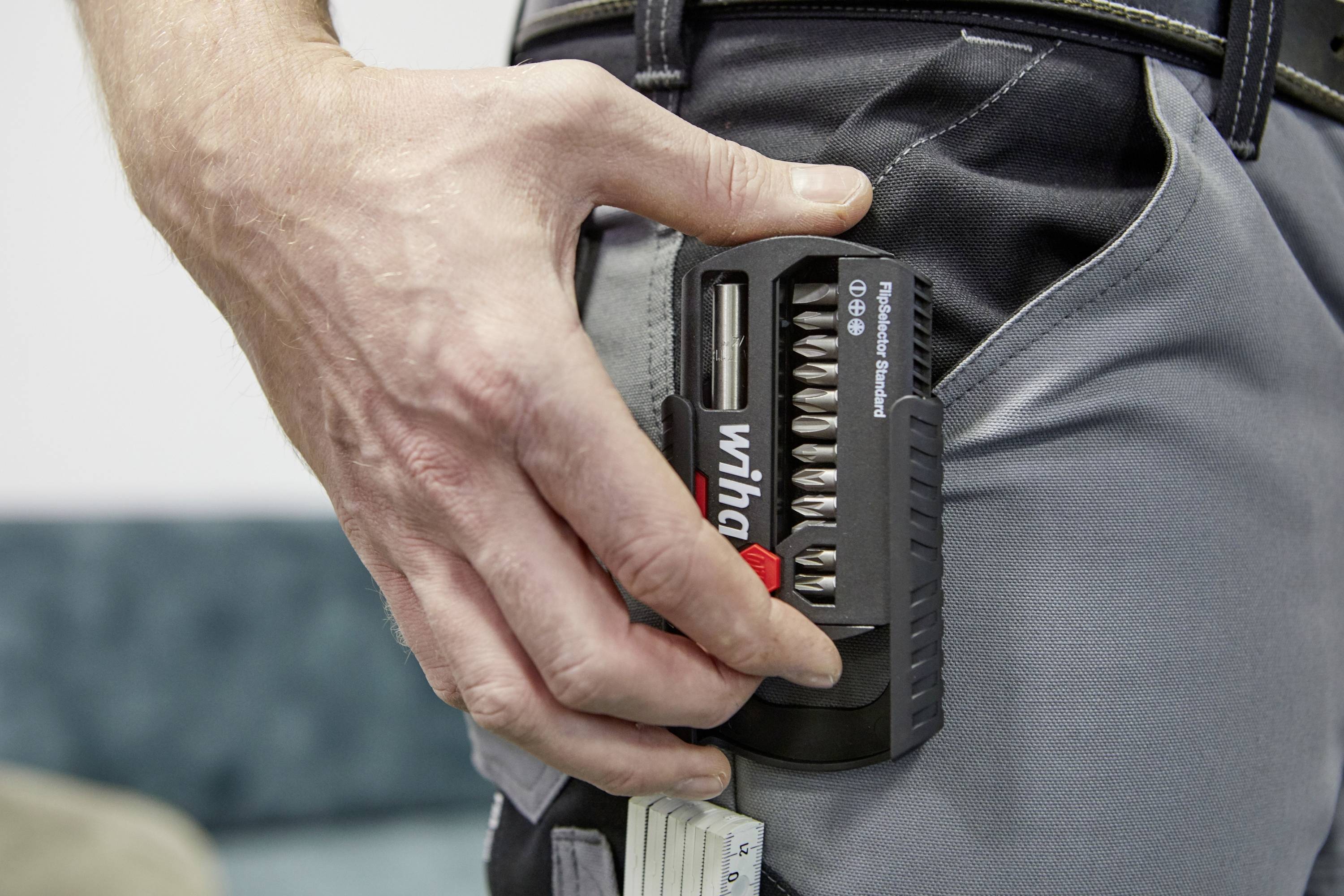 Ręka wyciąga zestaw bitów marki Wiha z torby. Zestaw zawiera różne końcówki wkrętakowe.