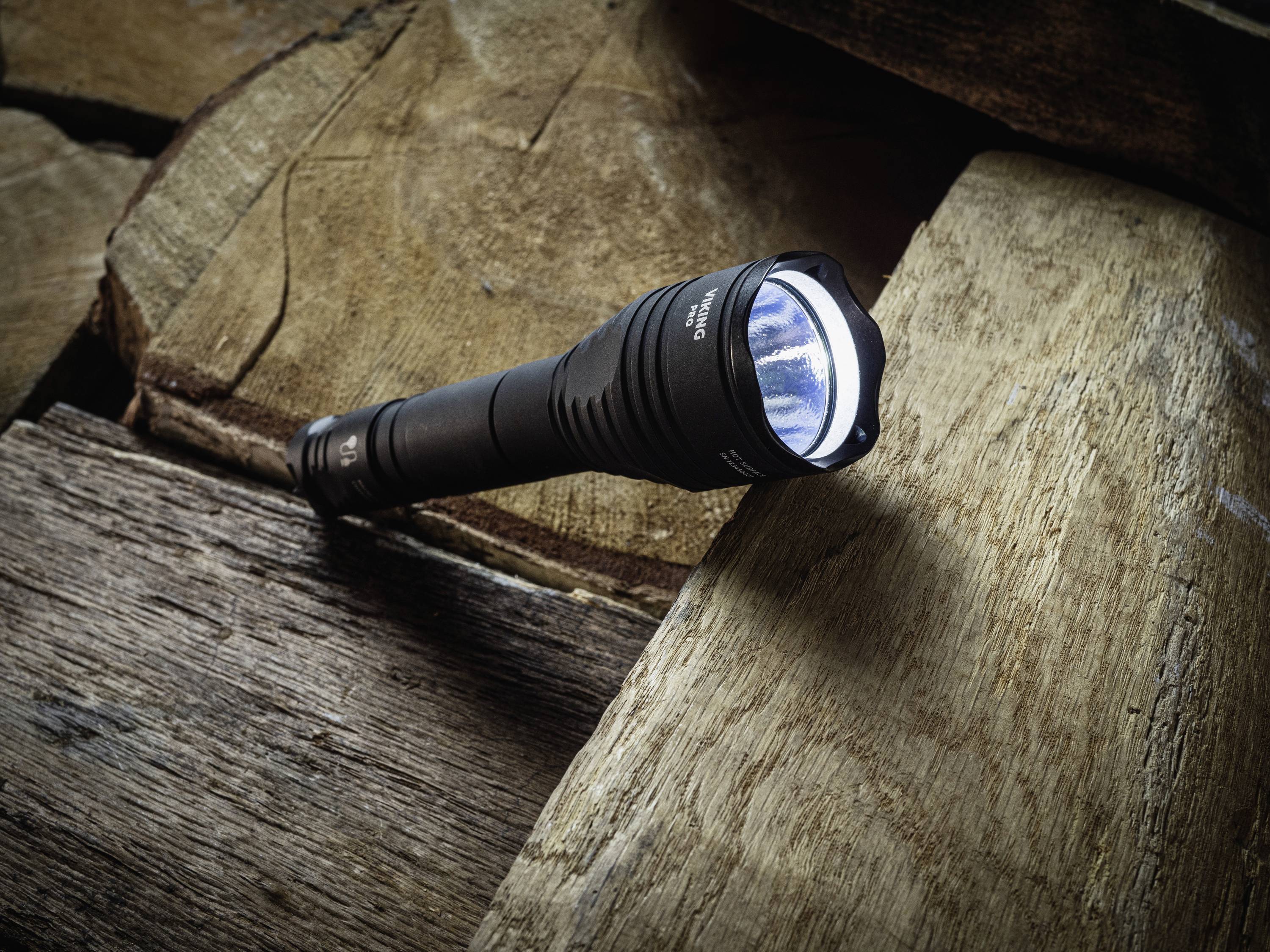 Latarka świeci na drewnianej powierzchni. Scena jest dobrze oświetlona i wyraźnie ukazuje teksturę drewna.