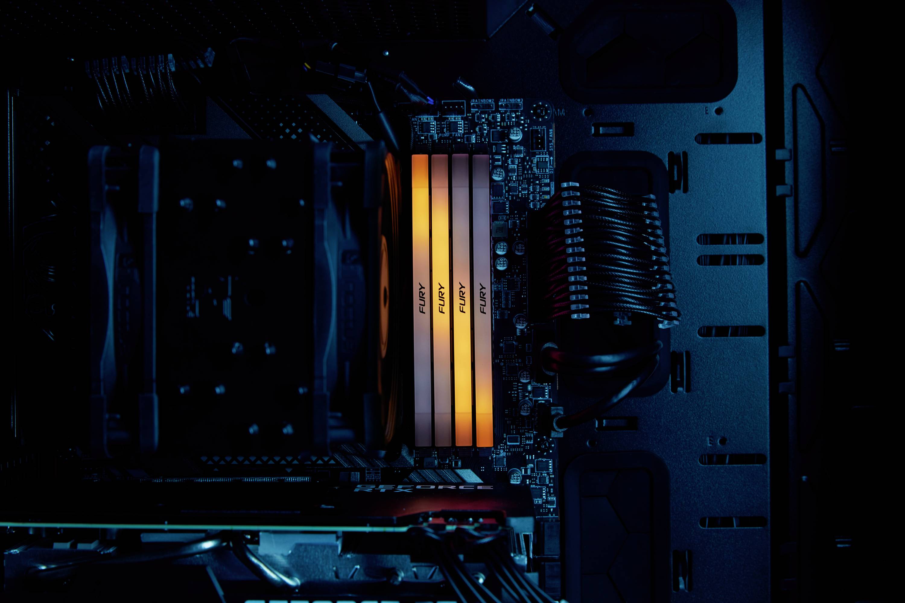 Widok wewnętrzny podświetlanego obudowy komputera z podświetlanymi modułami RAM i chłodzeniem, prezentujący nowoczesną konfigurację komputera PC.