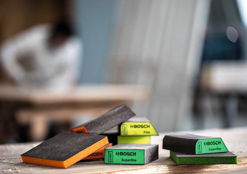 Bloki szlifierskie o różnych ziarnistościach na blacie stołu, rozmyty tło ukazuje środowisko warsztatu.