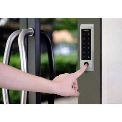 Ręka naciska klawisze elektronicznego zamka numerycznego na szklanych drzwiach, aby uzyskać dostęp.