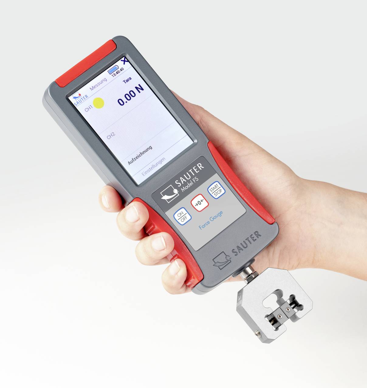 Jedna ręka trzyma cyfrowy miernik siły z wyświetlaczem, który pokazuje 0,00 N. Urządzenie ma czerwoną i szarą obramówkę.