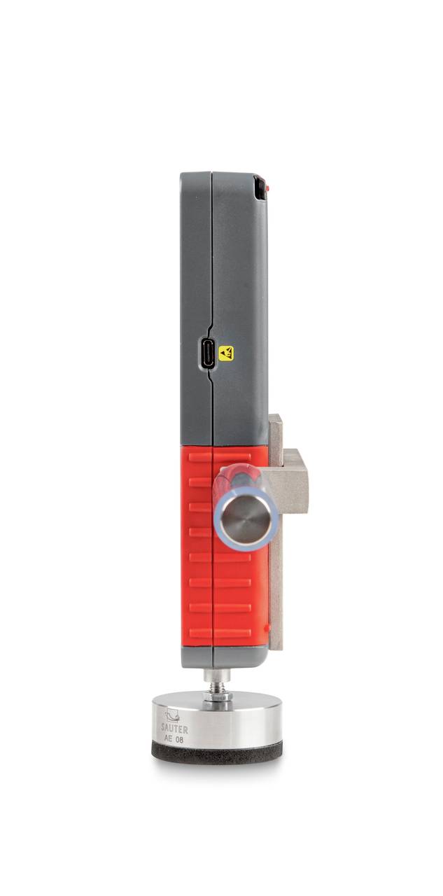 Czerwone i szare urządzenie przenośne z cylindryczną stopką czujnika, dźwignią boczną i złączem USB na górnej powierzchni.