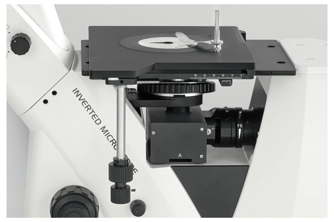 'Zbliżenie odwróconego mikroskopu z regulowaną platformą i pokrętłem ostrości, używanego do analizy próbek.'