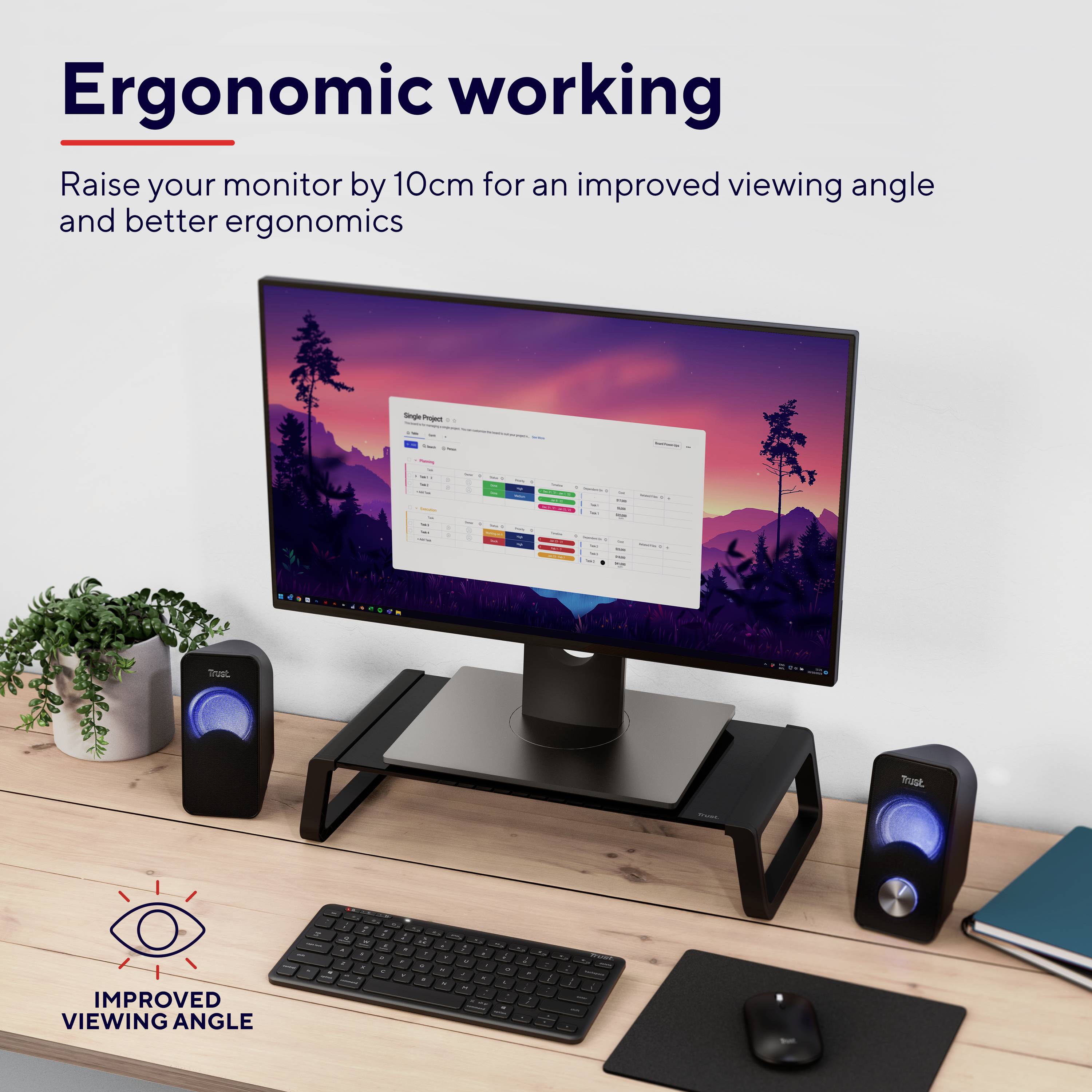 Monitor komputerowy na ergonomicznym stojaku podniesionym o 10 cm dla lepszej widoczności i ergonomii. Otoczony roślinami i głośnikami.