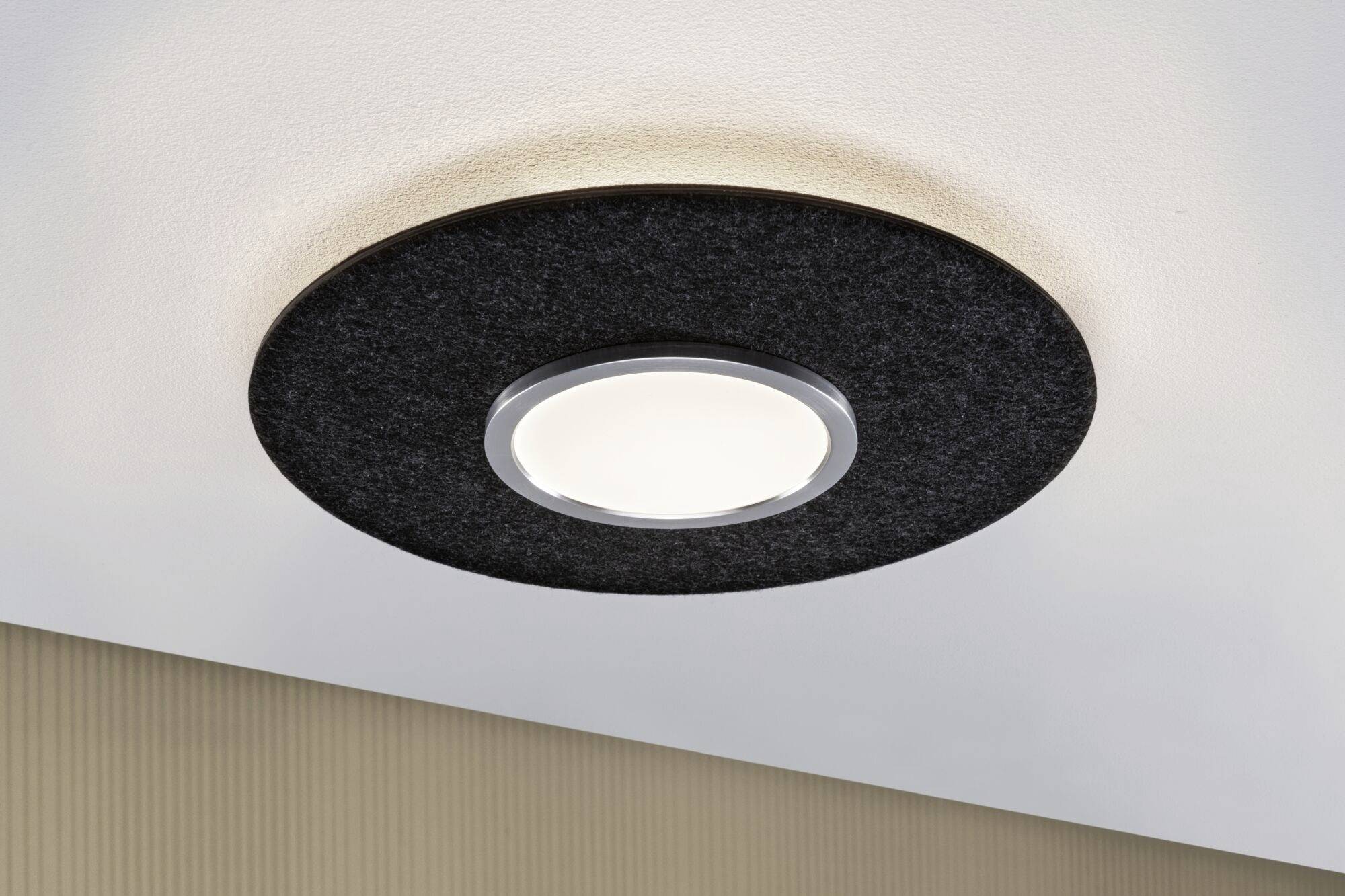 Okrągła lampa sufitowa z czarną ramą i jasnym światłem w nowoczesnym pomieszczeniu. Ma stylowy, minimalistyczny wygląd.
