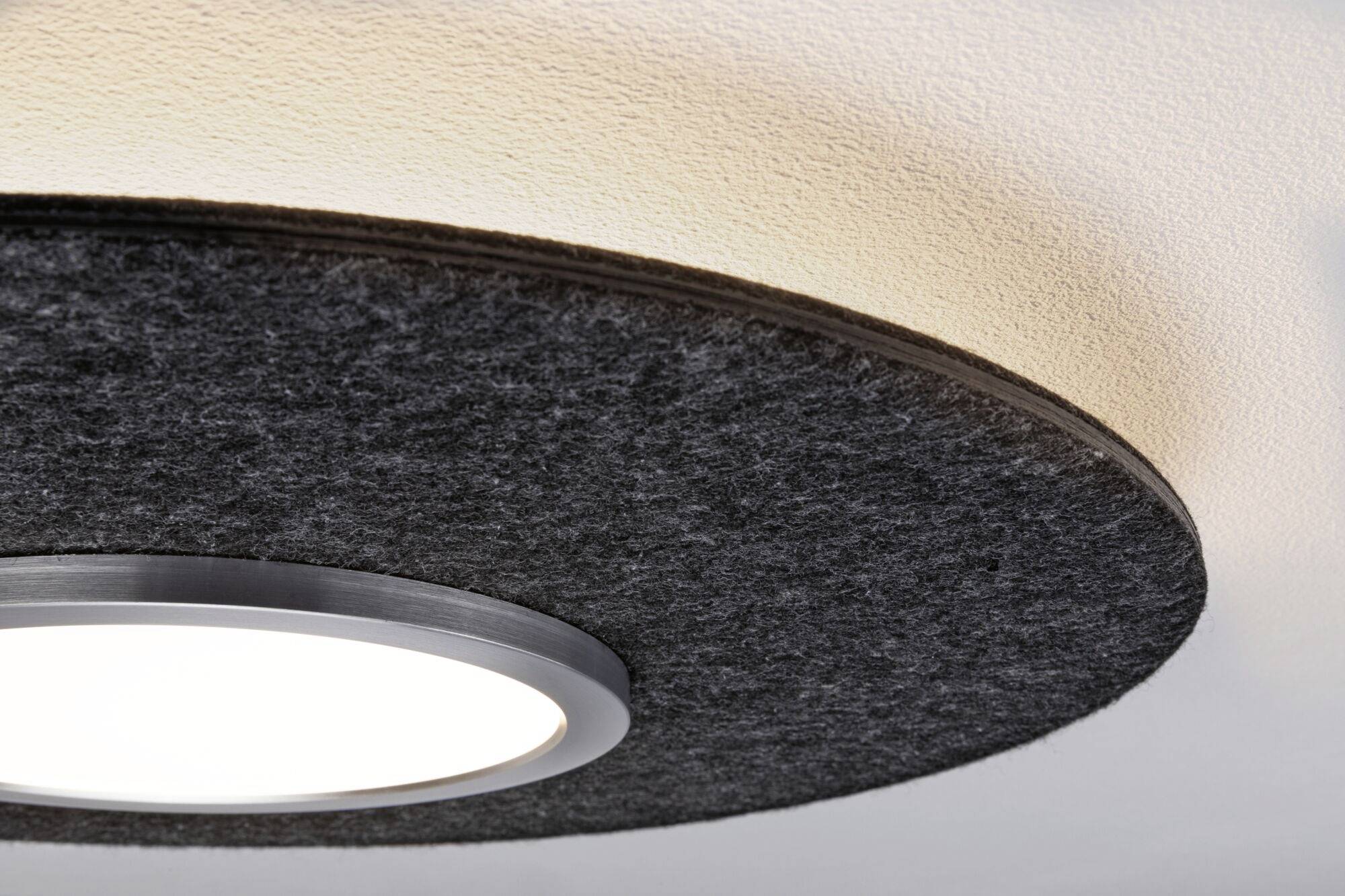 Lampa sufitowa z czarnym, okrągłym abażurem z filcu. Jasne światło pada w dół, zamocowana na białym suficie.