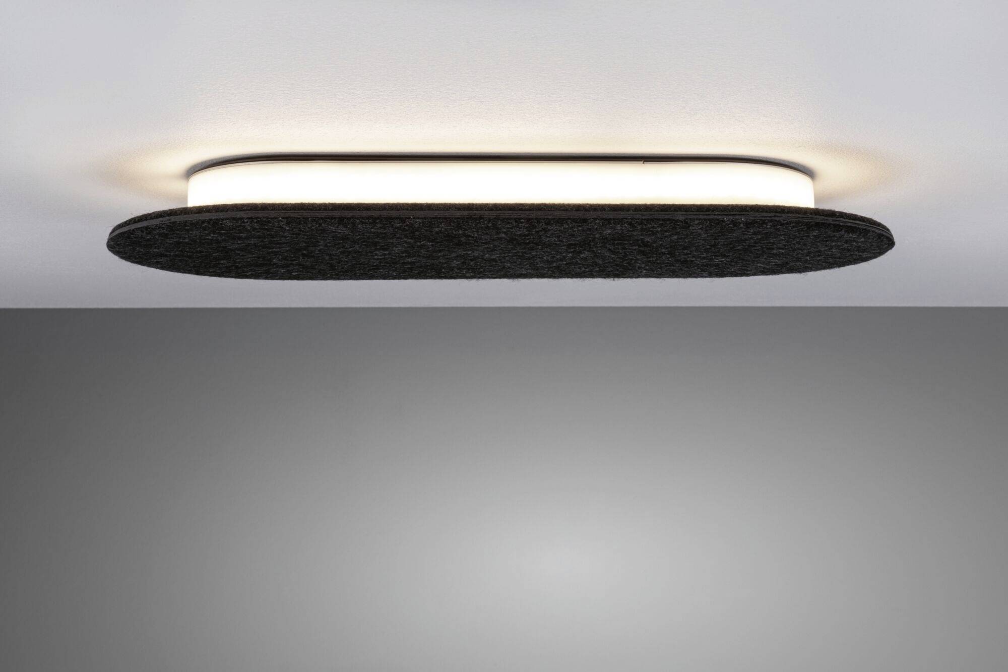 Lampa sufitowa z czarną ramą, emitująca miękkie, ciepłobiałe światło, zamontowana na szarym suficie.